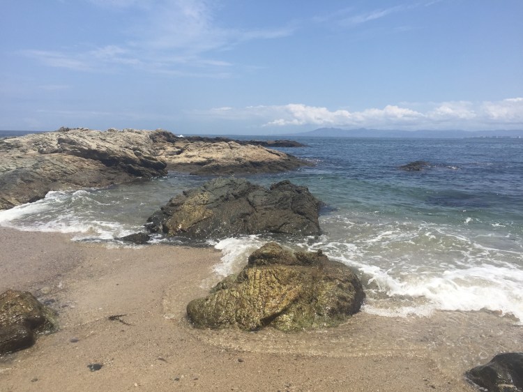 Photo is of small waves of water crashing onto the shore of a beach.