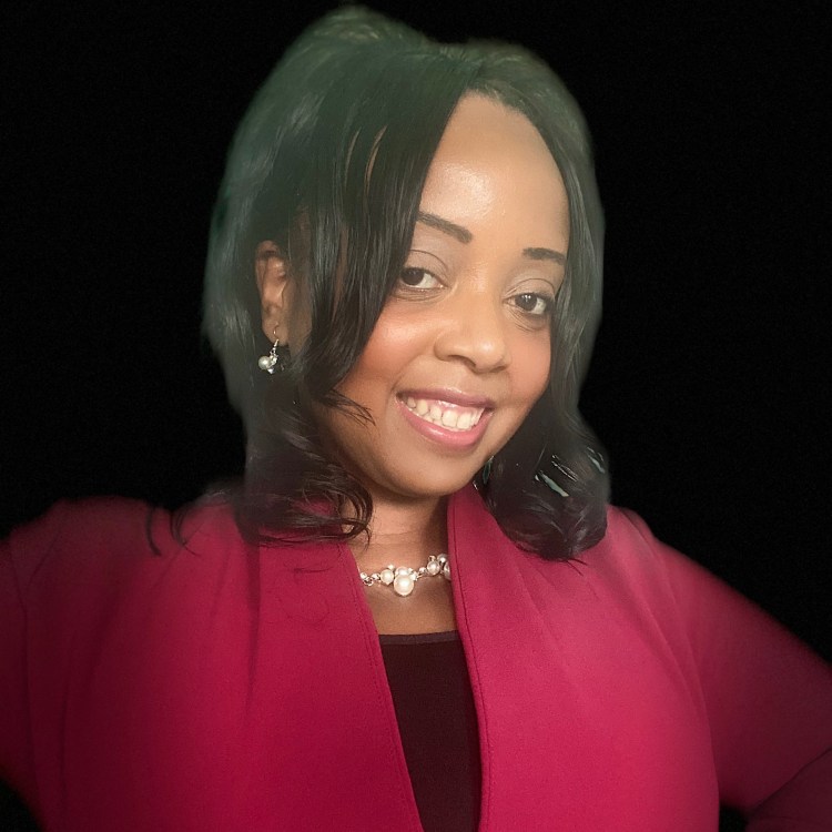 Photo is of Angel wearing a black and red shirt and necklace. The background is black.